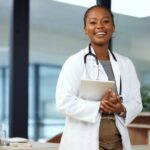 médica sorrindo segurando um tablet