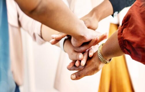 imagem de um time colocando as mãos uma sob as outras para ilustrar o conteúdo sobre testes genéticos como benefício corporativo