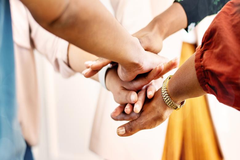 imagem de um time colocando as mãos uma sob as outras para ilustrar o conteúdo sobre testes genéticos como benefício corporativo